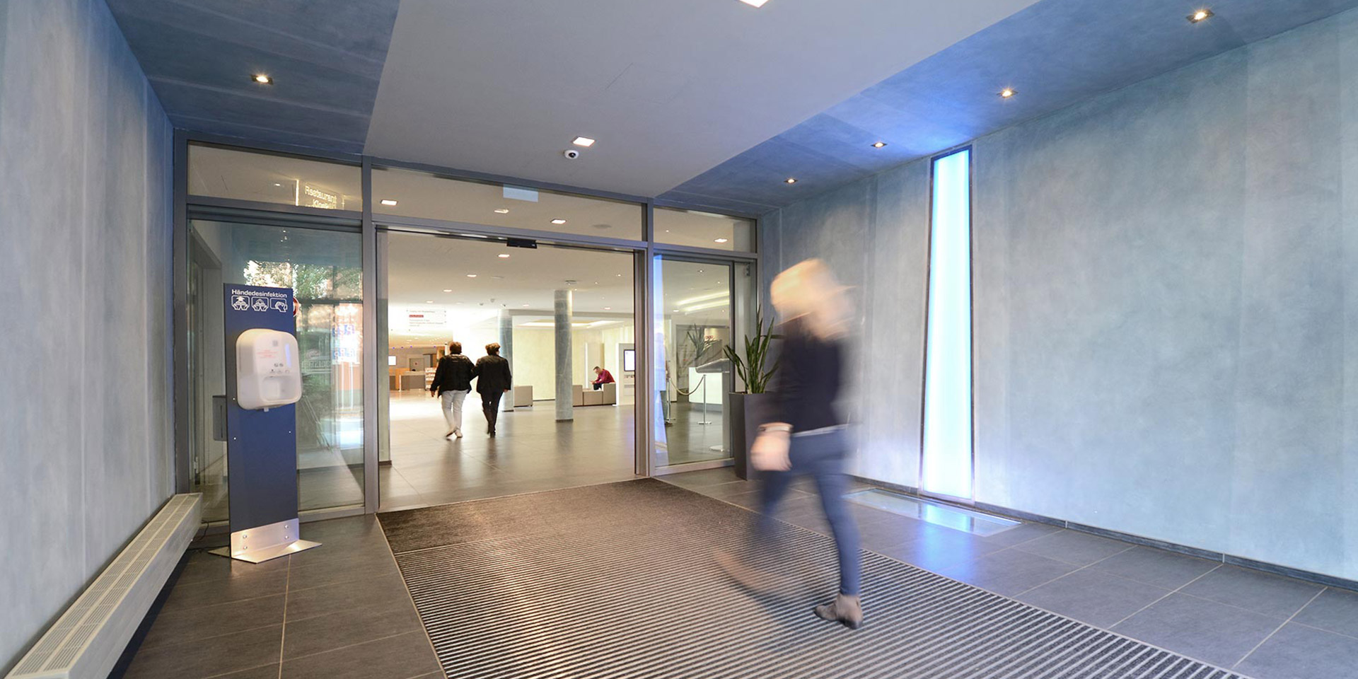 Frau geht durch den Eingangsbereich des EVK Mettmann ins Foyer des Krankenhauses.