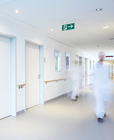 Pflegefachkräfte in weißen Kasacks gehen auf Stationsflur des EVK Mettmann – moderne Bildern sind an den Wänden.