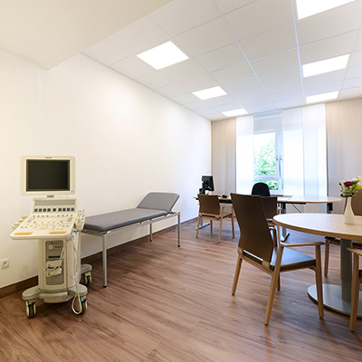Behandlungszimmer mit Ultraschallgerät, Patientenliege, Schreibtisch und Sitzbereich der Palliativstation im EVK Mettmann.