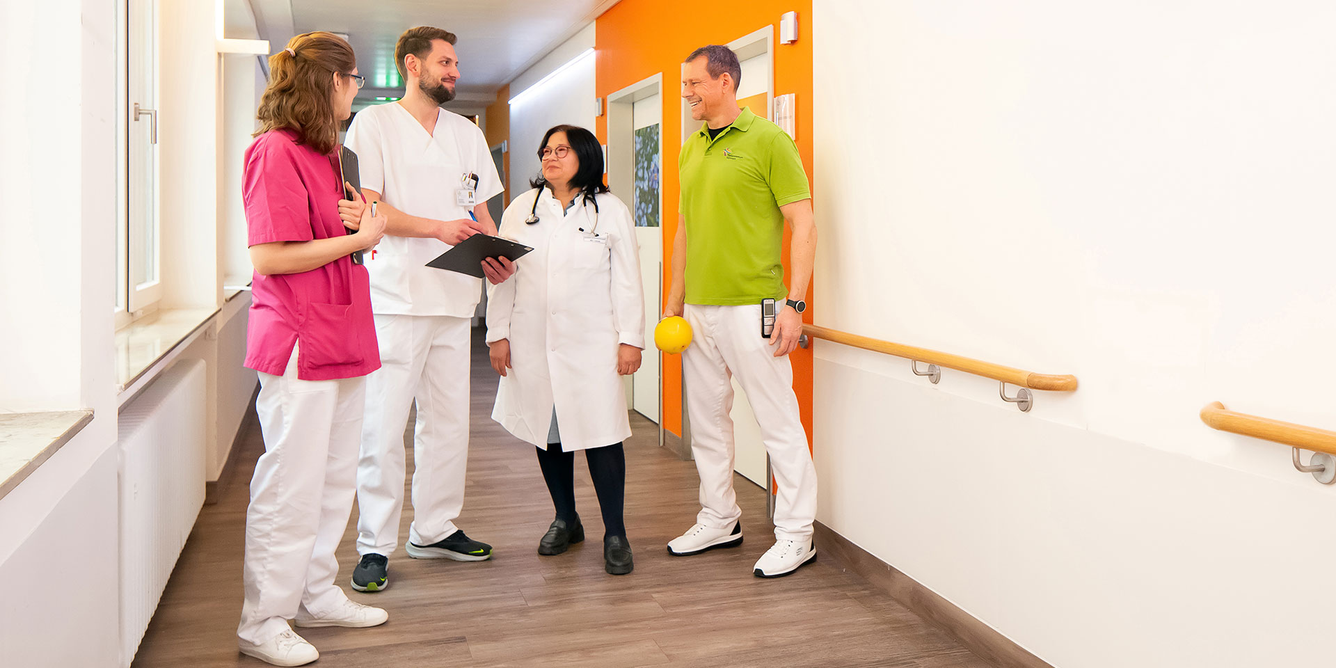 Ein Team aus verschiedenen Bereichen des EVK Mettmann im Gespräch vor einem Patientenzimmers auf der geriatrischen Station.
