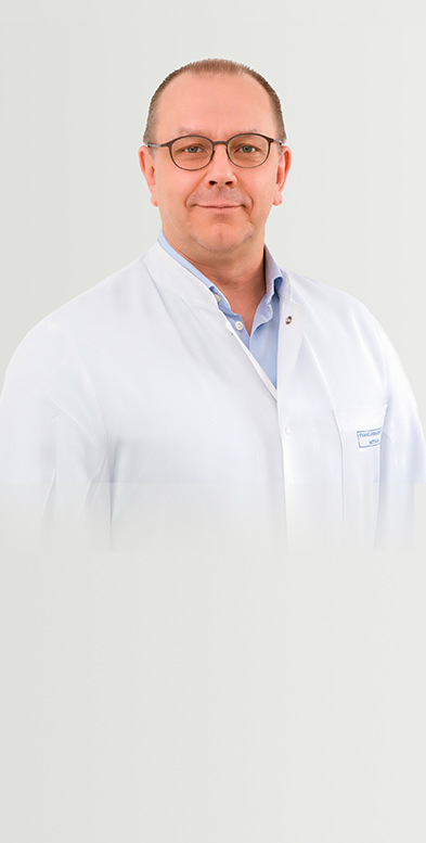 Porträtbild von Chefarzt Dr. med. Kamisnki auf grauem Hintergrund.