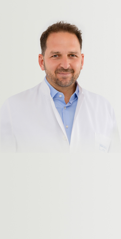 Porträtbild von Chefarzt Dr. med. Rossbach auf grauem Hintergrund.