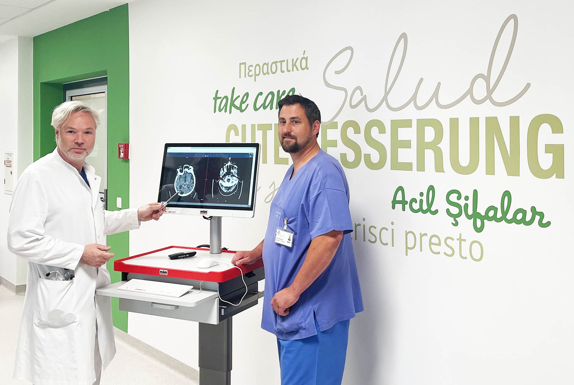 Chefarzt Prof. Dr. med. Bosche und Stationsleitung Herr Weishaupt stehen auf dem Flur der neuen Stroke Unit an einem mobilen Visitenwagen.